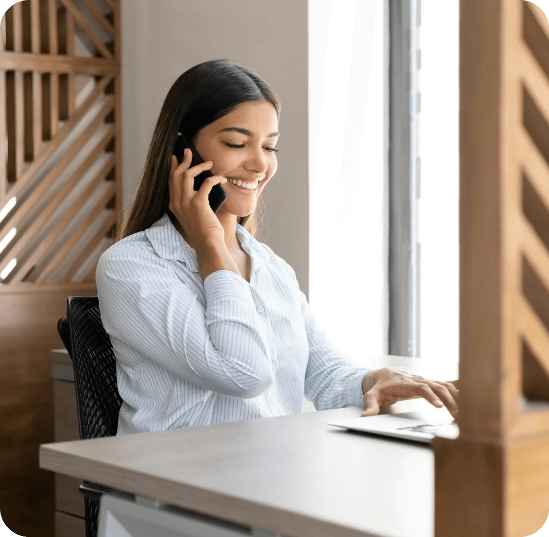 Smiling businesswoman talking on a phone while working at her desk