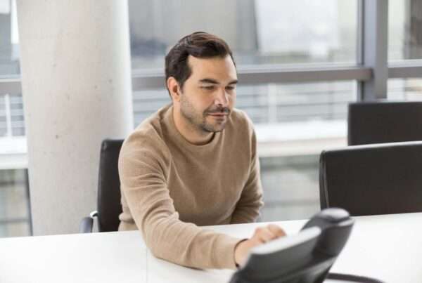 Professional using a desk phone in a modern office representing business phone service reviews