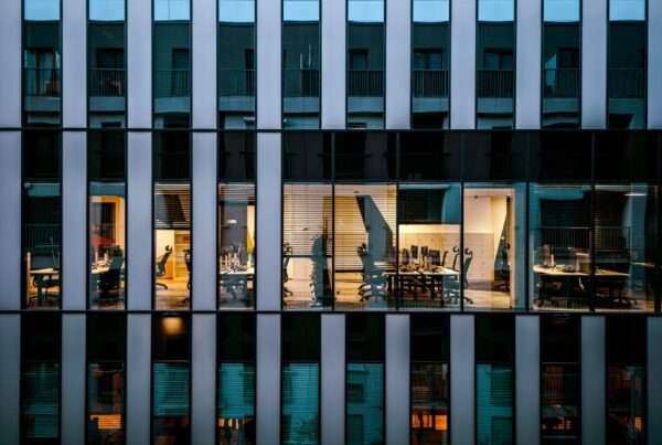 Modern glass commercial office building with illuminated tenant offices representing building-wide Wi-Fi and internet connectivity for multi-tenant commercial properties