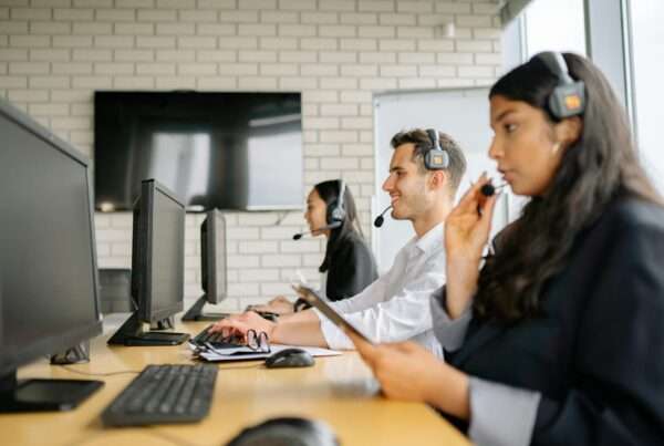 10 Best NiCE CXone Alternatives for Your Contact Center in 2025 4 Contact center representatives at workstations, representing contact center platform options
