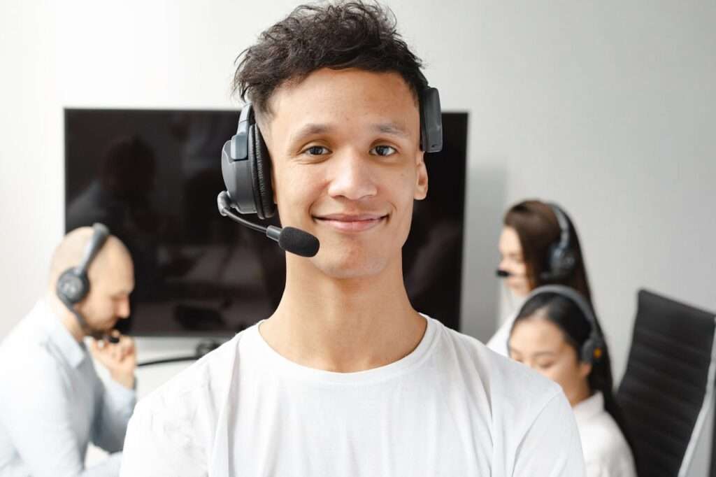 A professional call center agent wearing a headset, smiling while assisting a customer