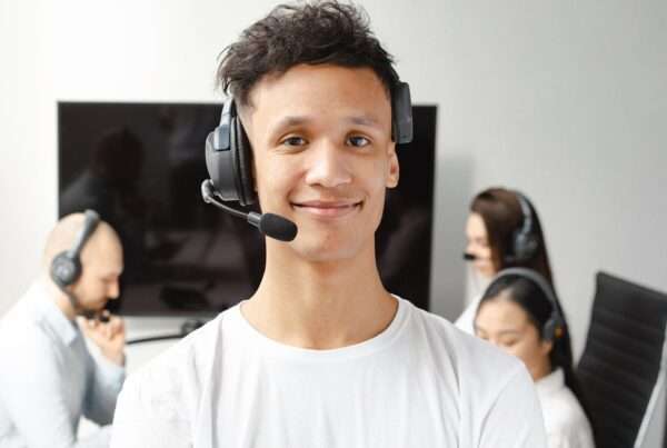 A professional call center agent wearing a headset, smiling while assisting a customer