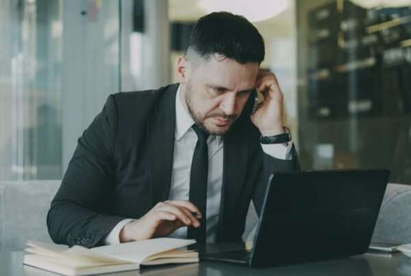 Don't Let a Price Increase Drive a Bad Decision: What to Consider Before Switching Business Phone Providers 6 Focused business professional in a suit working on a laptop and phone evaluating business communication provider options
