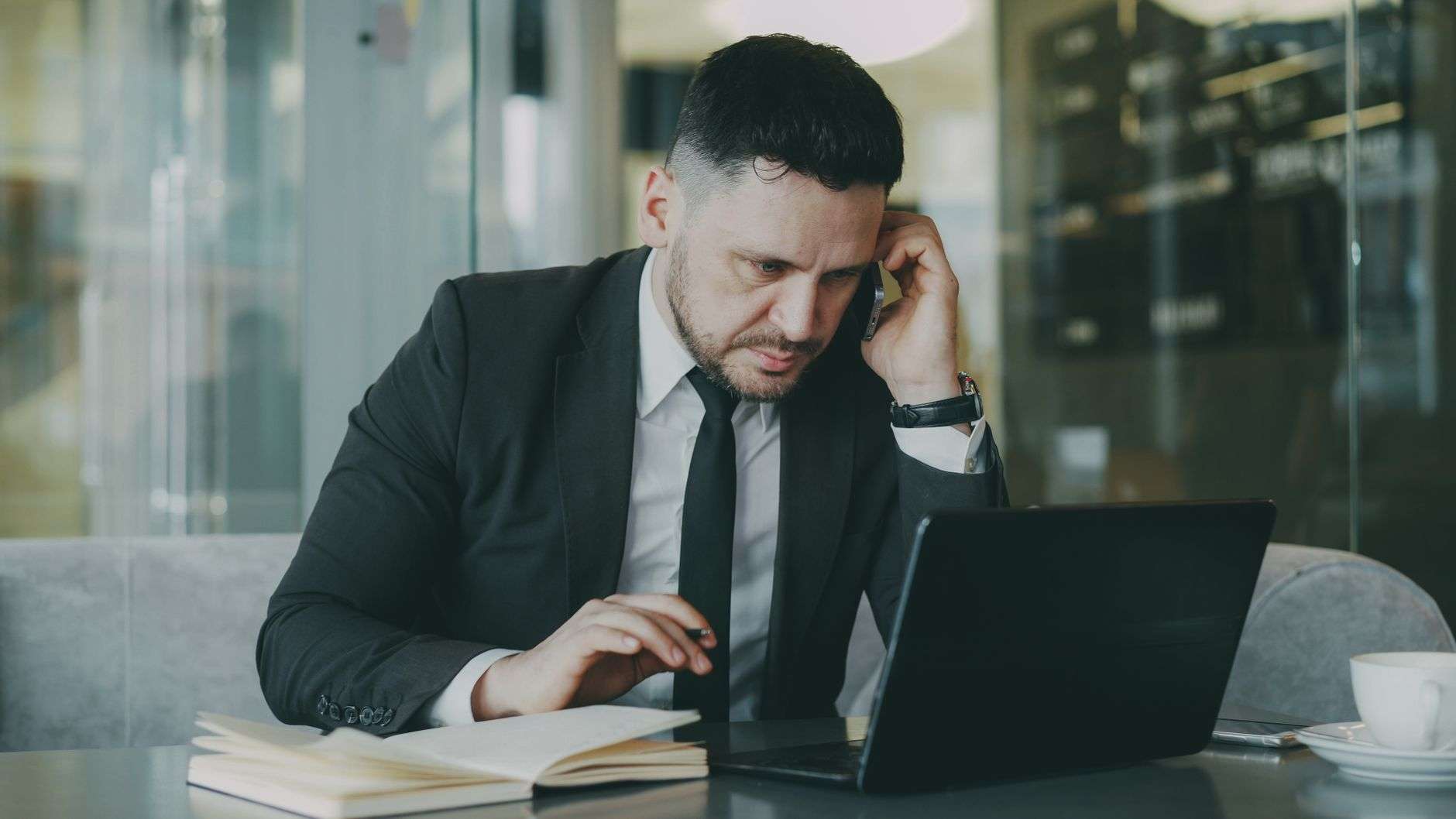 Focused business professional in a suit working on a laptop and phone evaluating business communication provider options