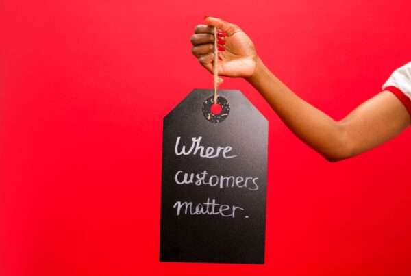 A hand holding a customer service tag emphasizing customer relationships and reviews