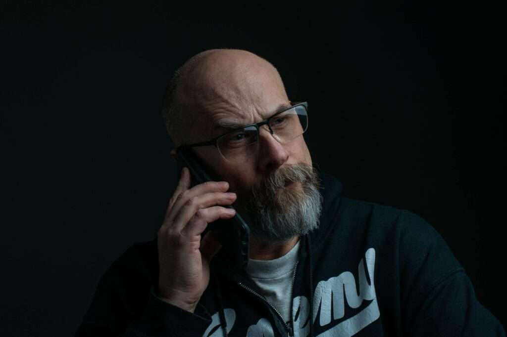 How to Detect and Prevent Deepfake Voice Fraud in Your Contact Center 3 Caller holding a phone in low light, representing deepfake voice fraud targeting contact centers