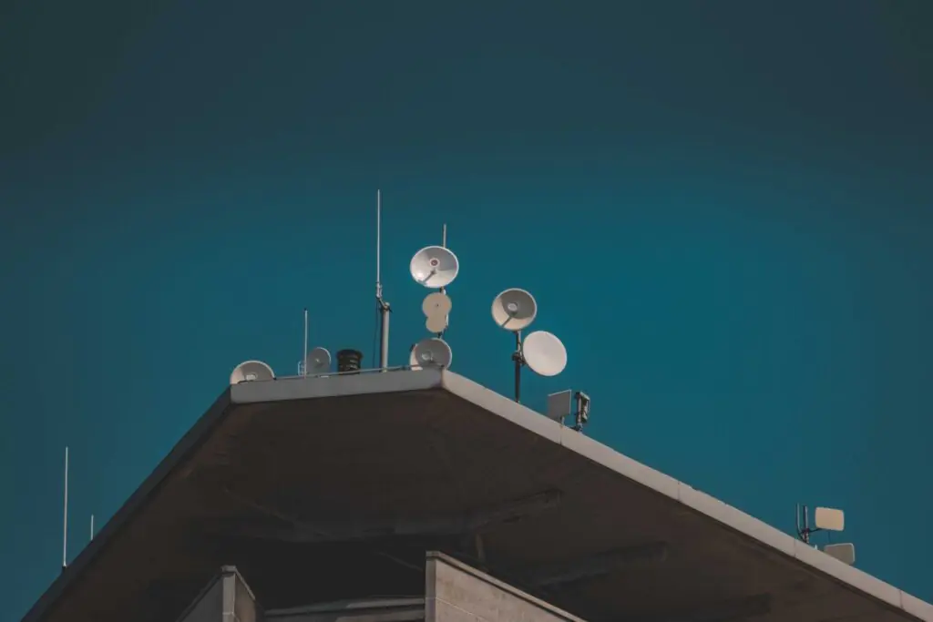 Directional point-to-point microwave dish antennas mounted on a building against a clear blue sky, used for high-bandwidth campus connectivity