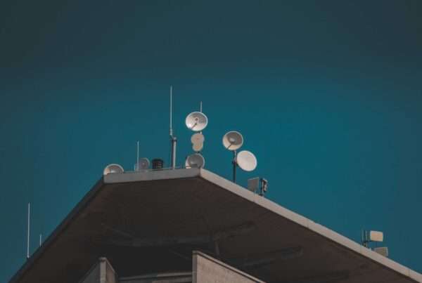 Directional point-to-point microwave dish antennas mounted on a building against a clear blue sky, used for high-bandwidth campus connectivity