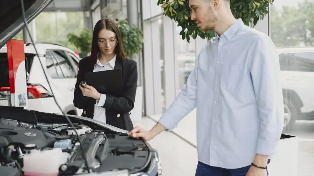 Service advisor and customer reviewing a vehicle together in a dealership service area, representing AI-powered call answering and appointment booking for auto dealerships