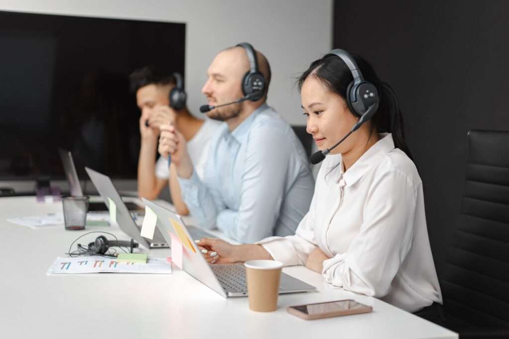 Customer support agents wearing headsets and working at laptops while handling business phone calls