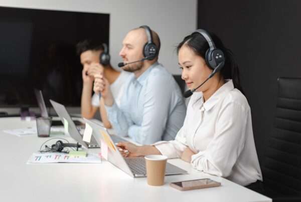 Customer support agents wearing headsets and working at laptops while handling business phone calls