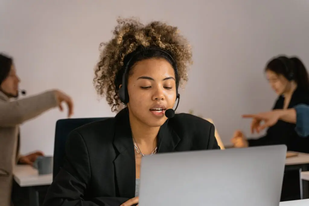 Customer support agent using AI-assisted software on a laptop while wearing a headset