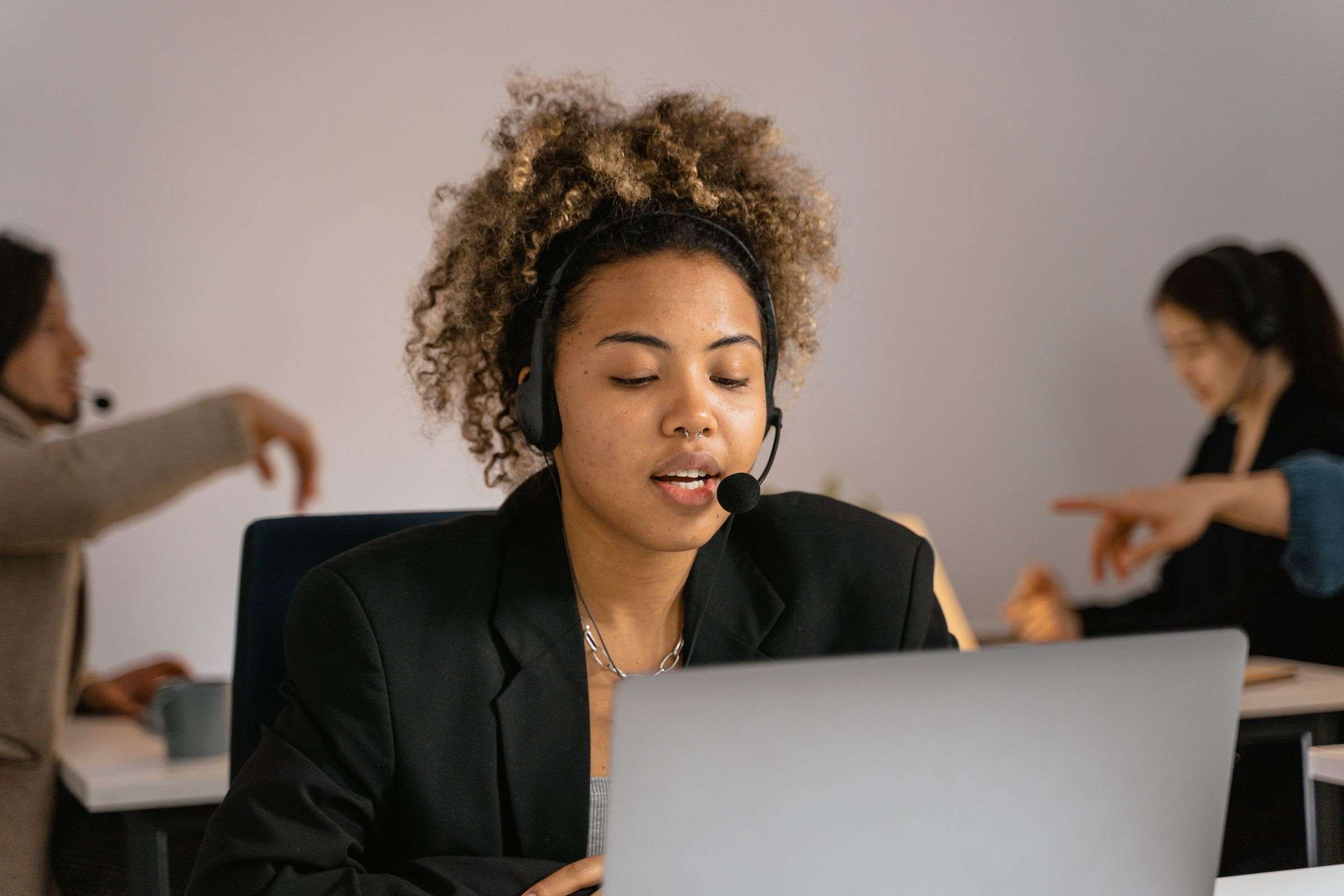 Customer support agent using AI-assisted software on a laptop while wearing a headset
