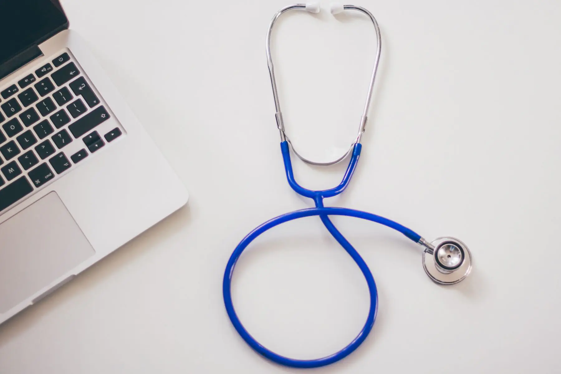 Stethoscope resting beside an open laptop on a desk, representing digital security for healthcare practices