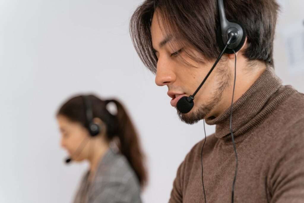Customer support agents wearing headsets assisting customers at computers in a modern office