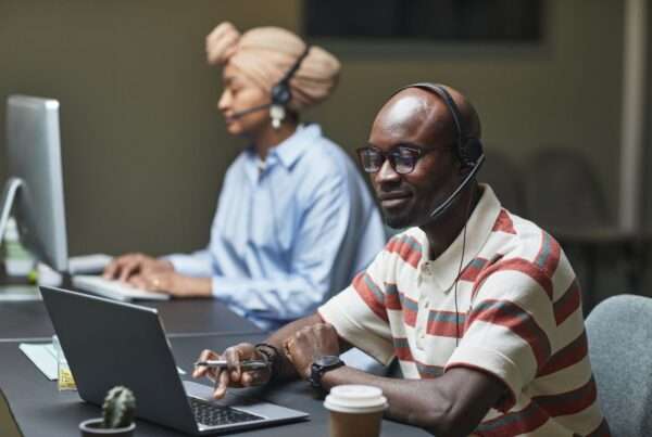 Two customer support professionals wearing headsets answering calls in an office at night