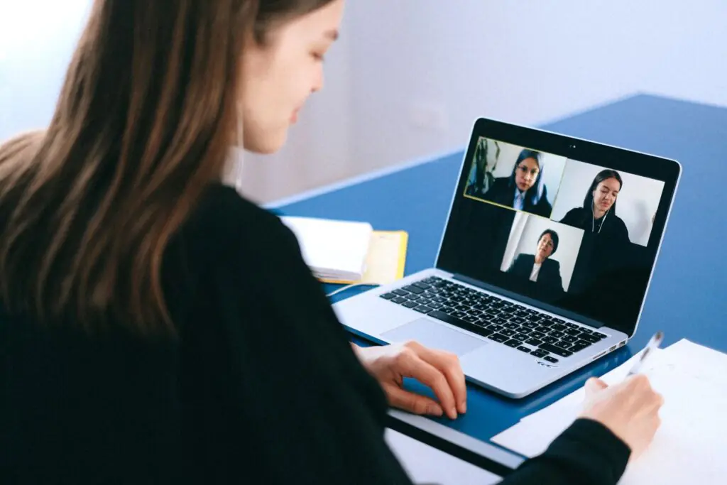 Professional taking notes during a video call on a laptop