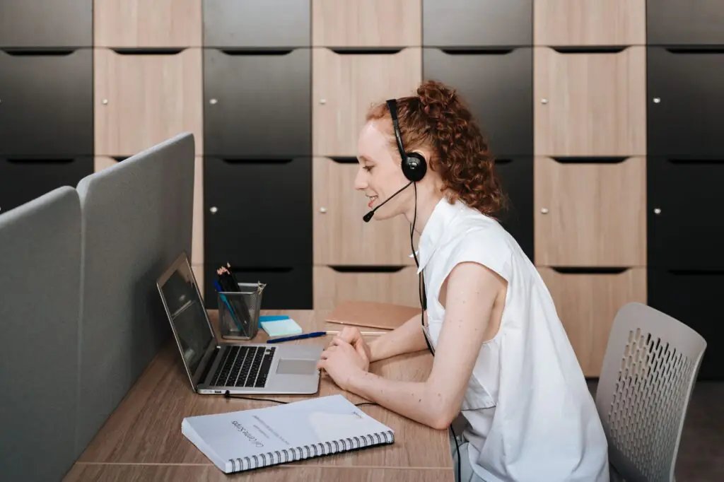 Professional wearing a headset while taking a business call at a laptop in an office