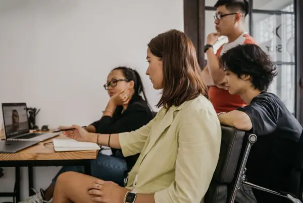 Four colleagues in a modern office collaborating on a video conference call using business communication apps
