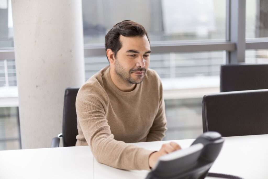 What Is a SIP Phone? A Business Guide to VoIP Calling 3 Business professional in a modern office using a VoIP desk phone to make a business call