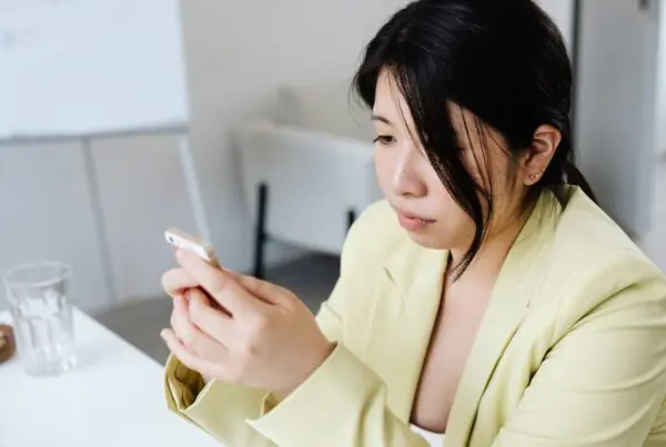 Professional woman at an office table sending a business text message on her smartphone