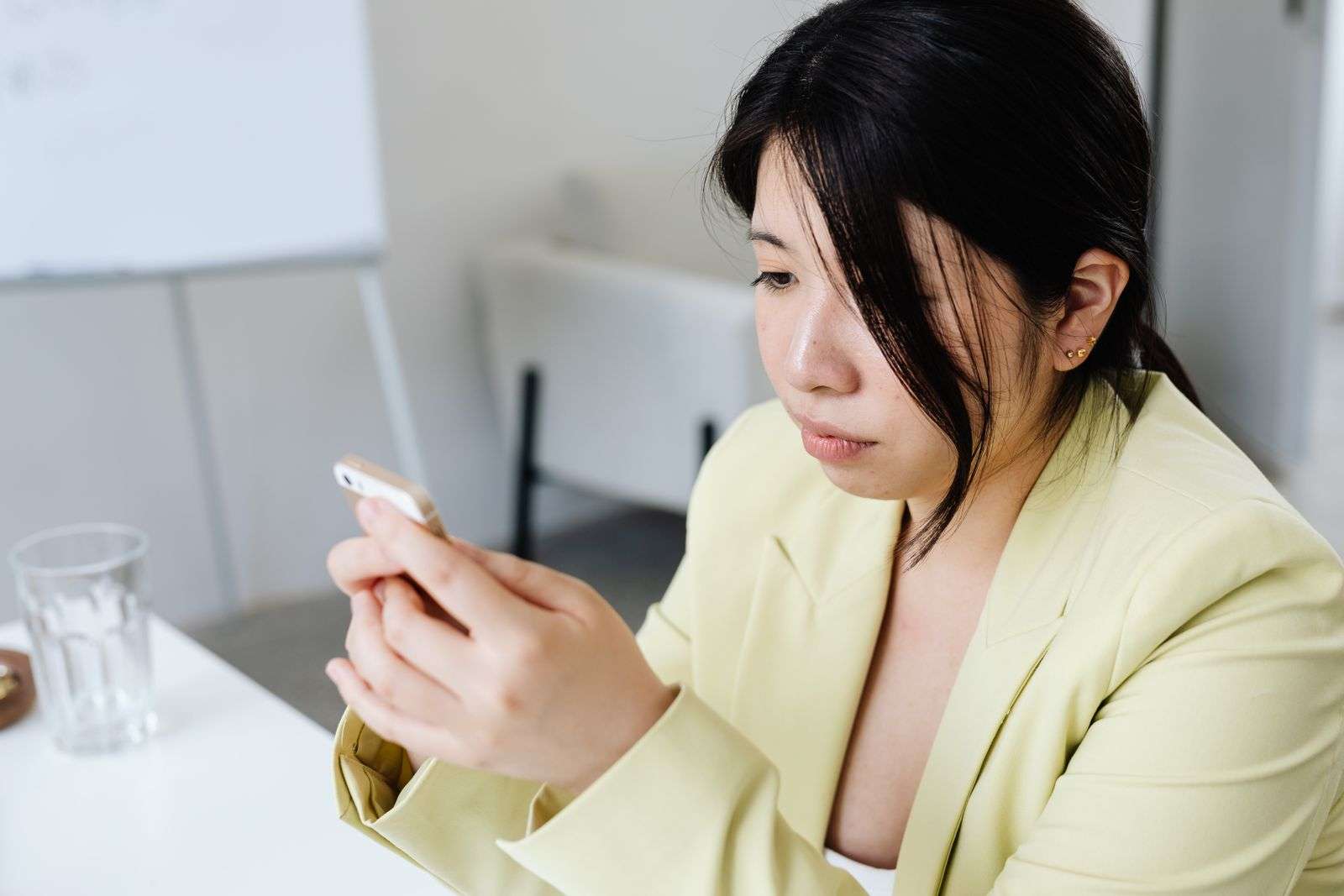 Professional woman at an office table sending a business text message on her smartphone