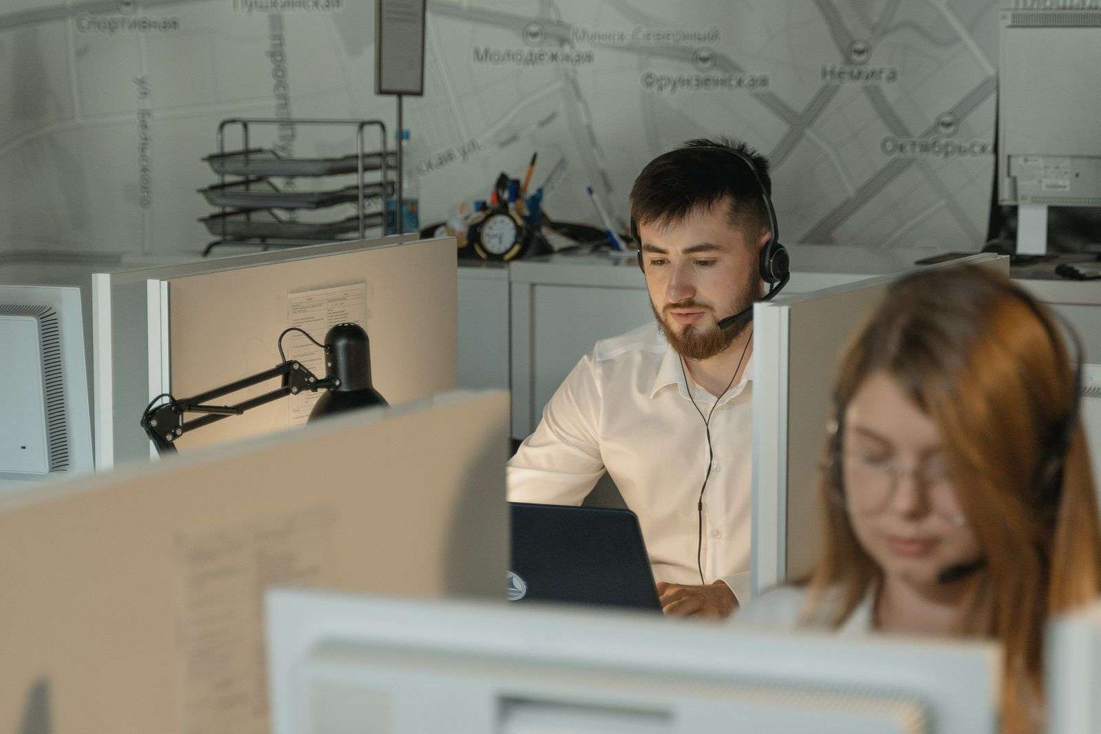 UCaaS vs. CCaaS: Choosing the Right Fit 2 Call center agent wearing a headset while working at a computer in an office contact center