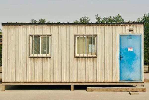 Temporary construction job trailer on a desert building site with a wireless antenna mast mounted on the roof for internet service