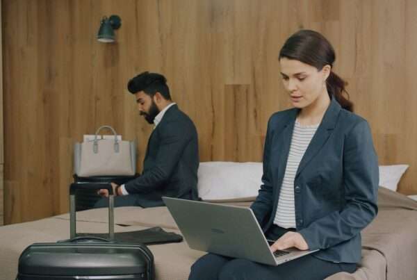 Hotel room desk with a laptop, tablet and phone connected to guest Wi-Fi while a streaming show plays on the room television