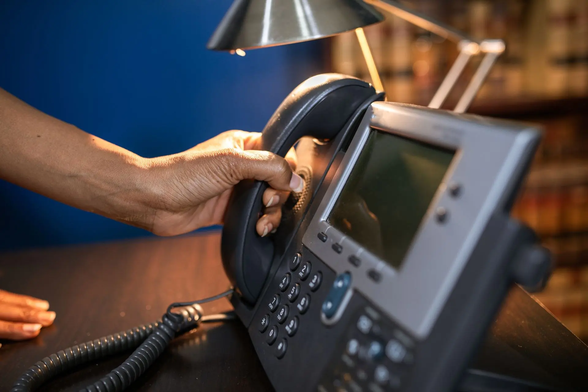 When to Replace Your Business Phone System: A Practical Self-Audit for 2026 1 A hand lifting the handset of a black office desk telephone, illustrating a business phone system audit and replacement evaluation