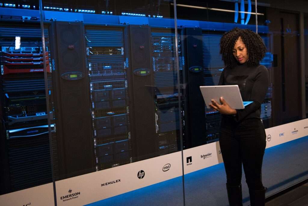 IT engineer using a laptop to monitor network servers in a data center to prevent downtime and security risks