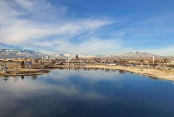 Reno, Nevada skyline reflected in a calm lake with the snow-capped Sierra Nevada mountains behind it