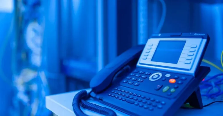 Modern business desk phone with a color display and keypad under blue lighting