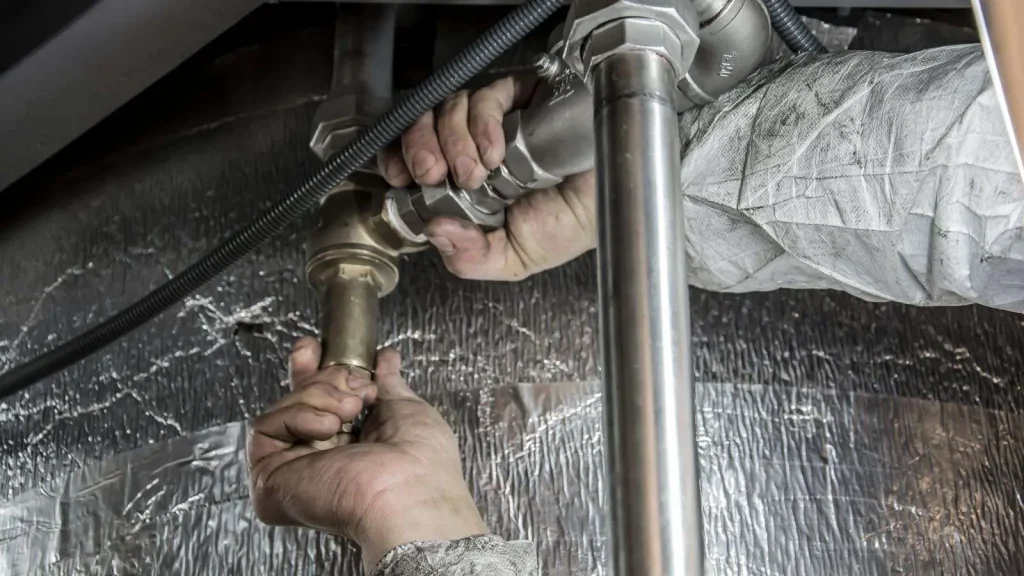 Technician installing steel pipework on a job site, representing AI answering services that book appointments and triage emergencies for plumbing, HVAC, and electrical businesses