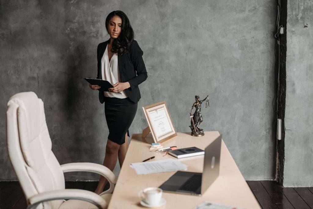 Professional reviewing documents in an office with a scales of justice statue on the desk