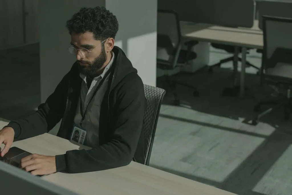 Security professional at a desk reviewing threat alerts on a laptop as part of an AI-assisted cybersecurity program