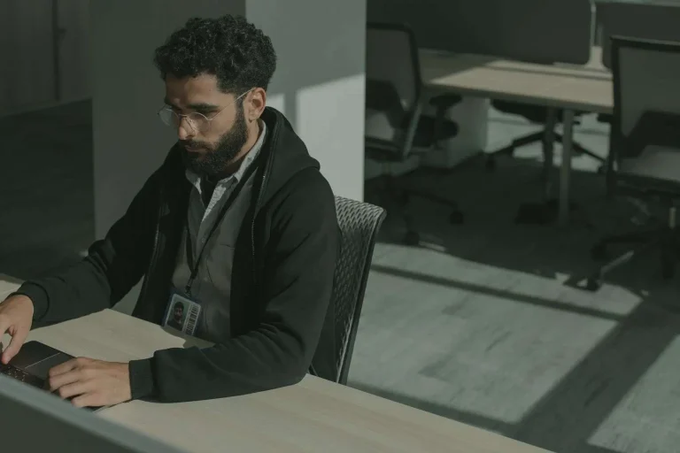 Security professional at a desk reviewing threat alerts on a laptop as part of an AI-assisted cybersecurity program