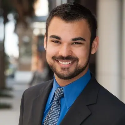 Headshot of a smiling man in a dark suit and blue tie