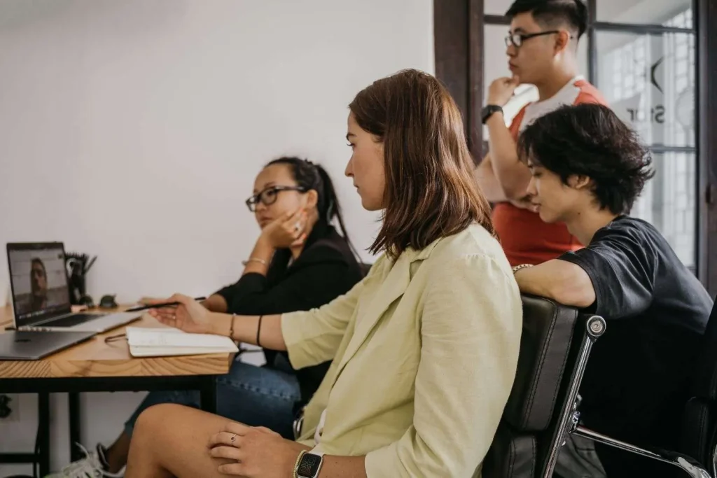Four colleagues in a modern office collaborating on a video conference call using business communication apps