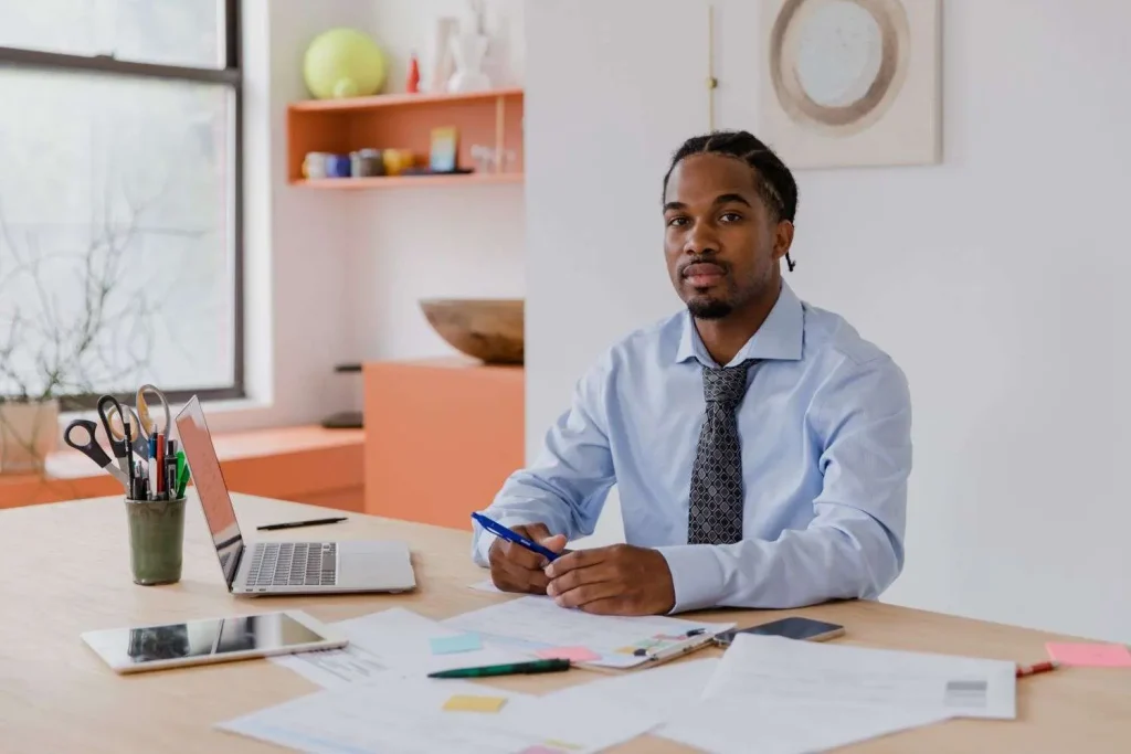 Small business owner sitting at a desk reviewing paperwork and a laptop while planning where to start a new company
