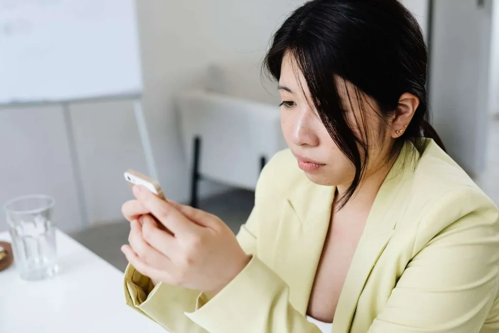 Professional woman at an office table sending a business text message on her smartphone