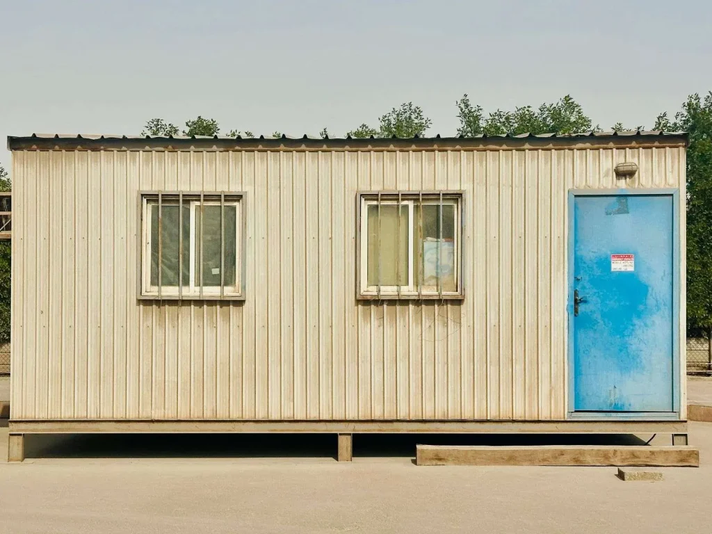 Temporary construction job trailer on a desert building site with a wireless antenna mast mounted on the roof for internet service