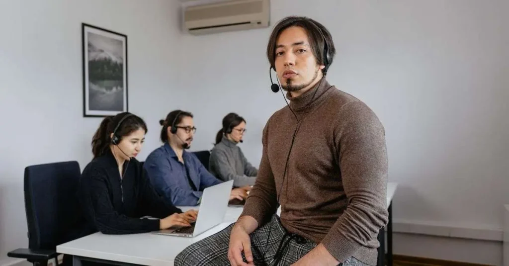 Contact center trainee wearing a headset seated in front of a team of agents in a training room