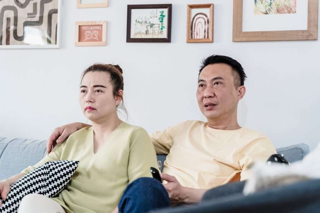 Couple relaxing on a sofa in a cozy living room while watching television together