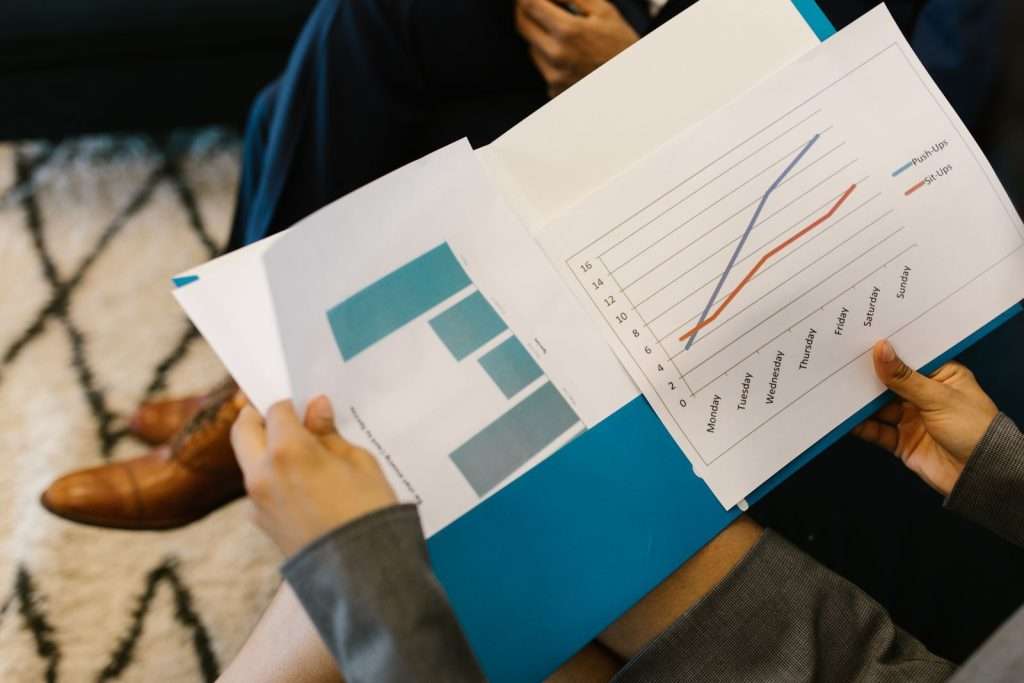 Two colleagues reviewing a printed business report with bar and line charts during a meeting