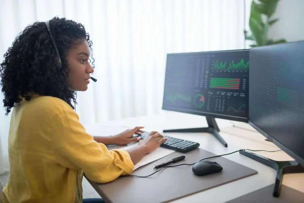 Business analyst reviewing customer experience data on dual computer monitors in an office