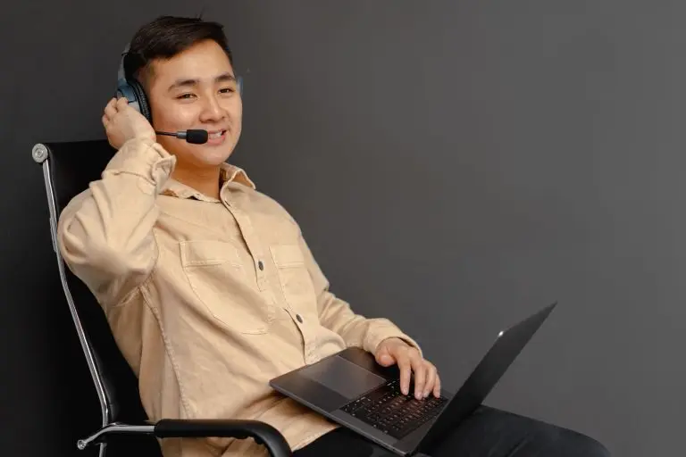 Smiling customer service agent wearing a headset with microphone while working on a laptop