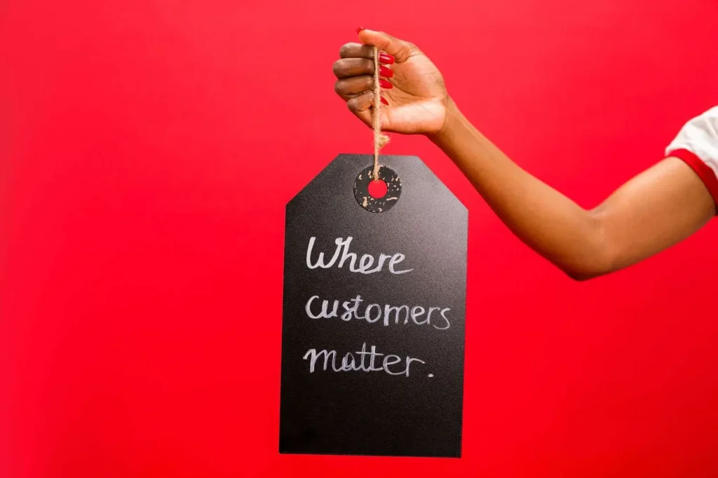 A hand holding a customer service tag emphasizing customer relationships and reviews