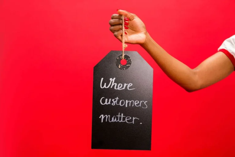 A hand holding a customer service tag emphasizing customer relationships and reviews