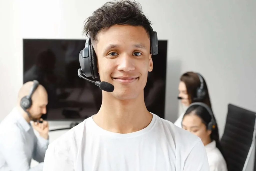 A professional call center agent wearing a headset, smiling while assisting a customer